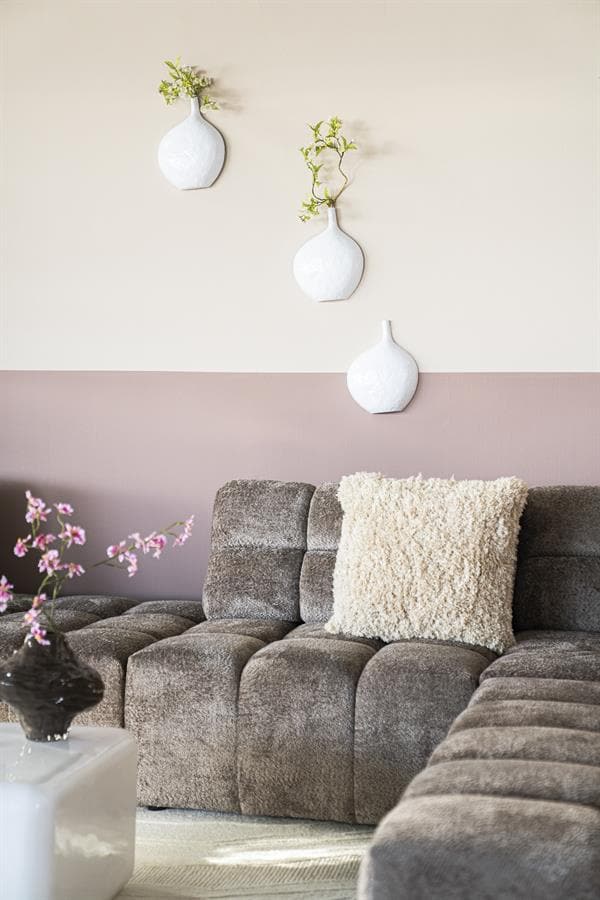 Stijlvolle woonkamer met moderne meubels, zachte kleuren en decoratieve witte vazen met groene takjes. Perfect voor een elegante en gezellige woonruimte.