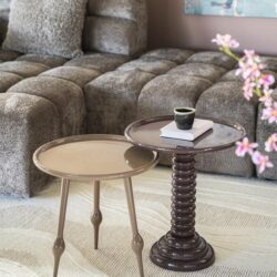 Stijlvolle woonkamer met beige lezen tafels en een comfortabele, grijze bank, perfect voor ontspanning en gezellige bijeenkomsten. Mooi gedecoreerd met bloemen en modern kunst aan de muur.