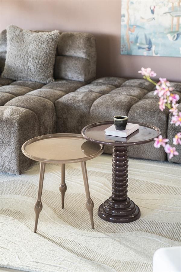 Stijlvolle woonkamer met beige lezen tafels en een comfortabele, grijze bank, perfect voor ontspanning en gezellige bijeenkomsten. Mooi gedecoreerd met bloemen en modern kunst aan de muur.