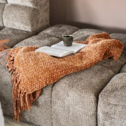 Knusse bank met aardewerk kleurige plaid en boeken op tafel, elegante woonkamer inrichting.