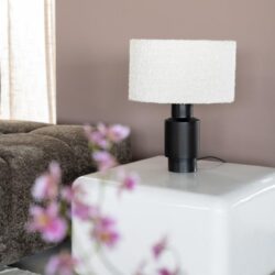 Moderne zwarte en witte tafel lamp op een witte bijzettafel in een woonkamer.
