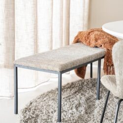 Eetkamerbank met metalen frame en gestoffeerd zitvlak in een modern binnenhuis.