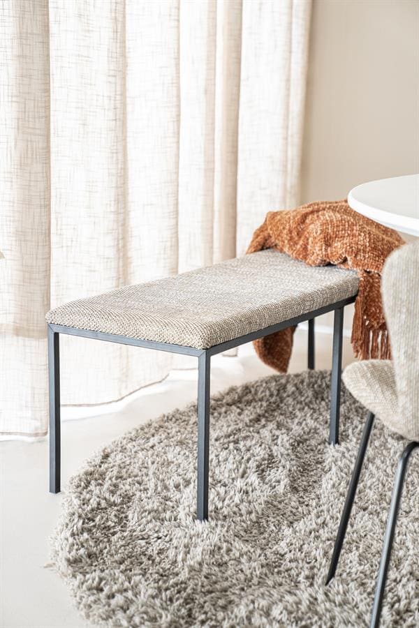 Eetkamerbank met metalen frame en gestoffeerd zitvlak in een modern binnenhuis.