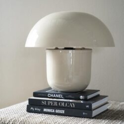 Modern witte tafellamp op gestapelde designboeken, elegant en stijlvol interieuraccessoire.