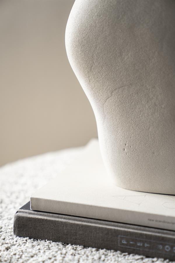 Elegante close-up van een wit keramisch vaas op boeken, stijlvol decor passend bij Mokana Meubelen, minimalistisch en modern interieur, natuurlijke kleuren, perfect voor stijlvolle woonaccessoires.