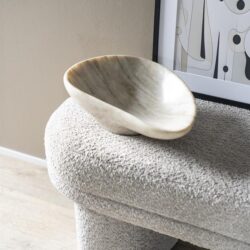 Moderne decoratieve schaal op een textured bank in een interieur, minimalistisch design, natuurlijke materialen, stijlvolle woonaccessoires, woontrend 2023.