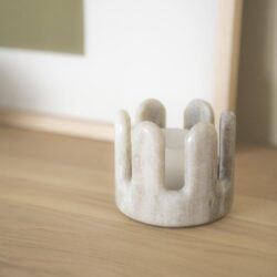 Elegante marmeren kaarsenhouder op een houten tafel, perfect voor moderne interieurdecoratie. Artikel van Mokana Meubelen, bekend om stijlvolle en hoogwaardige meubelstukken.