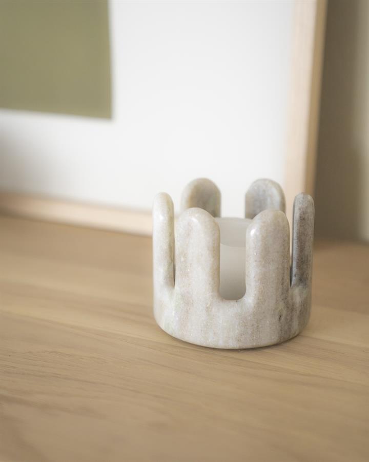 Elegante marmeren kaarsenhouder op een houten tafel, perfect voor moderne interieurdecoratie. Artikel van Mokana Meubelen, bekend om stijlvolle en hoogwaardige meubelstukken.