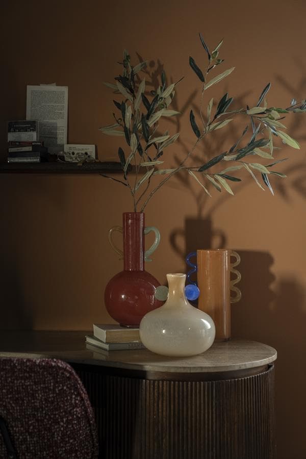 Vazen en decoratieve voorwerpen op een houten tafel met een boekenplank op de achtergrond, stijlvol en modern design van Mokana Meubelen.