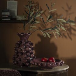 Botervaas met olijftakken en appels op bijzettafel voor een elegant interieur, vintage decor en stijlvolle woninginrichting.