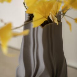 Grote close-up van een elegante, golvende vaas met gele bladeren en bloemen, perfect voor stijlvolle woonkamer decoratie.