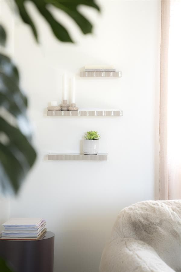 Strakke witte muur met div. decoratieve planken en een plant, stijlvolle en functionele meubels voor een modern interieur.