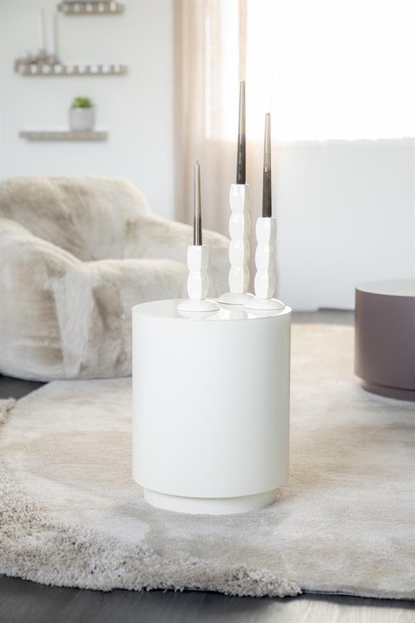 Strakke witte stooklampen op ronde witte tafel in strak modern interieur met zachte stoffen zithoek en lichte gordijnen.