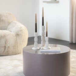 Elegant modern living room decor with a round gray coffee table and white candleholders, showcasing Mokana Meubelen's stylish furniture and interior design accessories.
