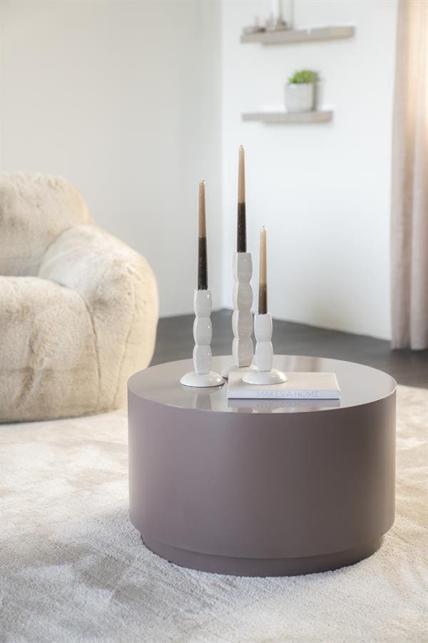 Elegant modern living room decor with a round gray coffee table and white candleholders, showcasing Mokana Meubelen's stylish furniture and interior design accessories.