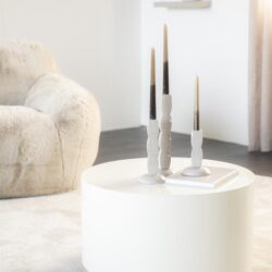 Kaarsenstandaard met drie kaarsen op wit bijzettafel in modern woonkamer.
