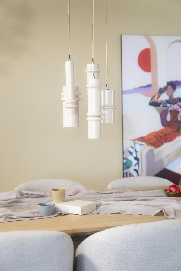 Moderne witte hanglampen boven een eettafel met comfortabele stoelen en stijlvolle decoratie, perfect voor een eigentijdse huisinrichting.