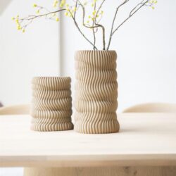Zachte beige keramische vazen met golvend reliëf op eettafel, decoratief bloemstuk, modern interieur, elegante woonaccessoires, natuurlijke materialen, design vaas, Mokana meubelen, interieurstyling.