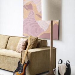 Decoratieve woonkamer met vintage bank, moderne lamp, sprekende muurkunst en elektrische gitaar voor een stijlvolle en praktische interieurstijl.