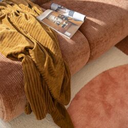 Mocha fluwelen bank met bijpassend vintage sierkussen en overzicht magazine, perfecte toevoeging aan een gezellige woonkamer met luxe en comfort.
