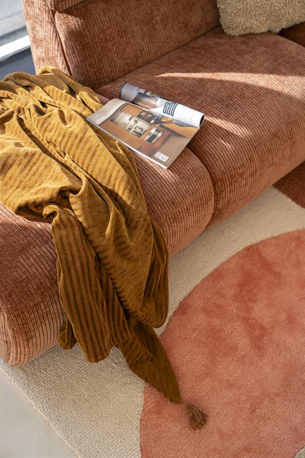 Mocha fluwelen bank met bijpassend vintage sierkussen en overzicht magazine, perfecte toevoeging aan een gezellige woonkamer met luxe en comfort.