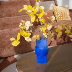 Blauwe vaas met gele bladeren op houten salontafel in modern woonkamer, uniek interieuraccessoire, duurzaam design, stijlvolle decoratie ideeën, Mokana Meubelen Nederlandse meubelwinkel.