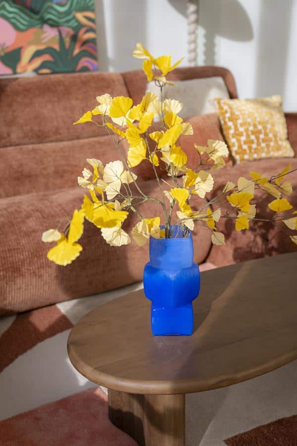 Blauwe vaas met gele bladeren op houten salontafel in modern woonkamer, uniek interieuraccessoire, duurzaam design, stijlvolle decoratie ideeën, Mokana Meubelen Nederlandse meubelwinkel.