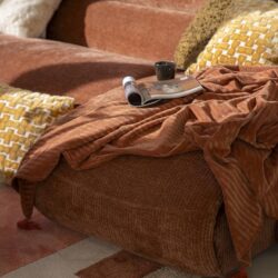 Rustkleurige bank met comfortabele kussens en een zacht deken, perfect voor ontspanning en gezelligheid in huis.