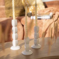 Stijlvolle witte en beige waxinelichthouders met gedraaide kaarsen op een houten salontafel in een gezellige woonkamer.