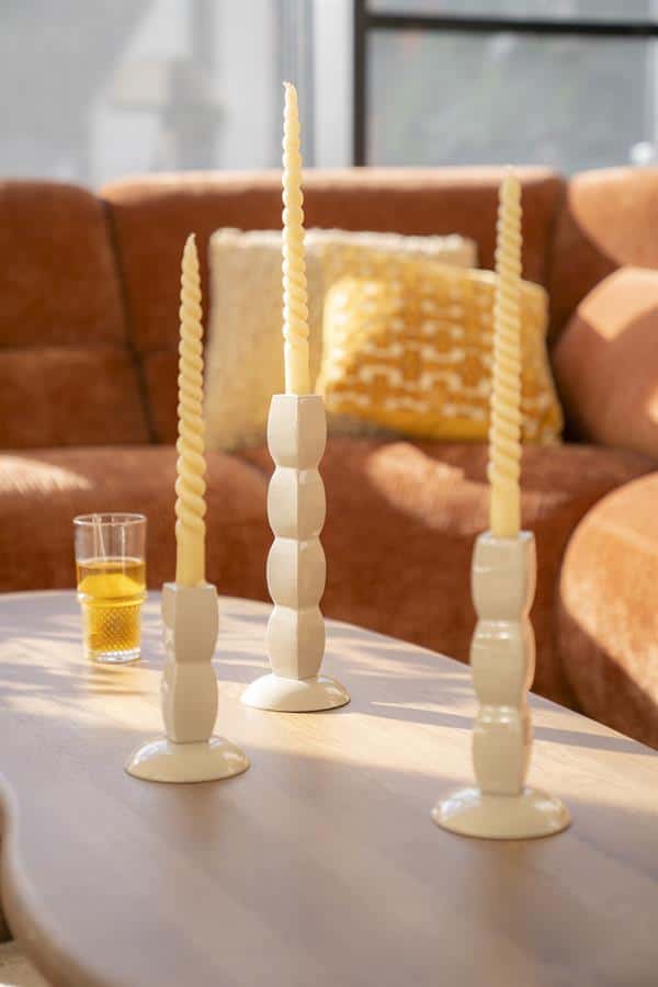 Elegante witte kandelaars met gedraaide kaarsen op een tafel, stijlvolle interieuraccessoires voor modern en warm wonen bij Mokana Meubelen.