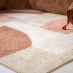 Luxe landelijk tapijt van moquette met geometrisch patroon in zand, blush en terracotta tinten, perfect voor een stijlvolle woonkamer.