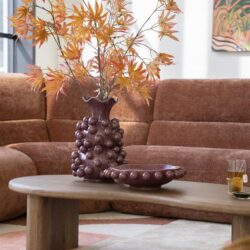 Zweefvazen met bladeren en houten salontafel in een modern woonkamer met bank en kunstwerk.