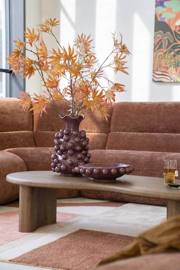 Zweefvazen met bladeren en houten salontafel in een modern woonkamer met bank en kunstwerk.