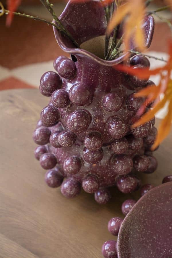 Zwartrode keramische vaas met bollen decoratief design op houten tafel, perfecte aanvulling voor modern interieur.