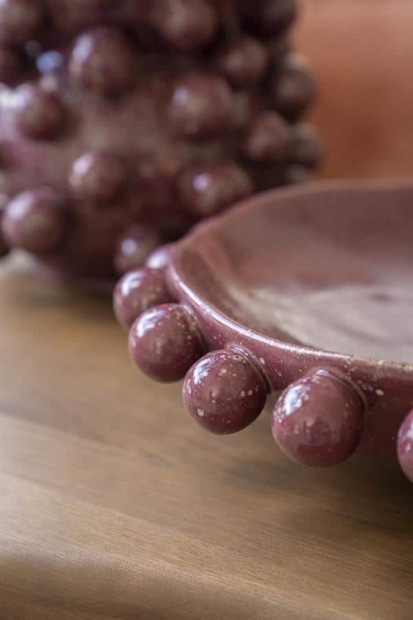 Kaasplankje met decoratieve bolletjes rand, vervaardigd uit keramiek in een warme, aardse tint, perfect voor servies en tafelsetting.