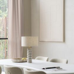 Minimalistisch eettafel met moderne lamp en zachte keukenstoelen in een lichte, sfeervolle woonkamer met natuurlijke lichtinval.