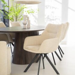 Strakke beige eetkamerstoelen met zwart metalen poten rondom een houten eettafel in een modern interieur.