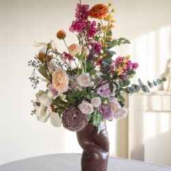Gevarieerd boeket bloemen in mooie keramieke vaas op tafel, elegant bloemstuk voor interieur decoratie, Mokana Meubelen, stijlvolle bloemenvaas, modern woonaccessoire, bloemstuk voor woninginrichting, kleurrijke bloemenarrangementen, inspiratie voor huisdecoratie, exclusieve bloemenvaas collectie, lachen met bloemen, elegant woonidee, bloemenstyling for home decor.