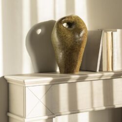 Krijtstenen vaas op witte console, modern decor, natuurlijke materialen, elegante woonaccessoire.