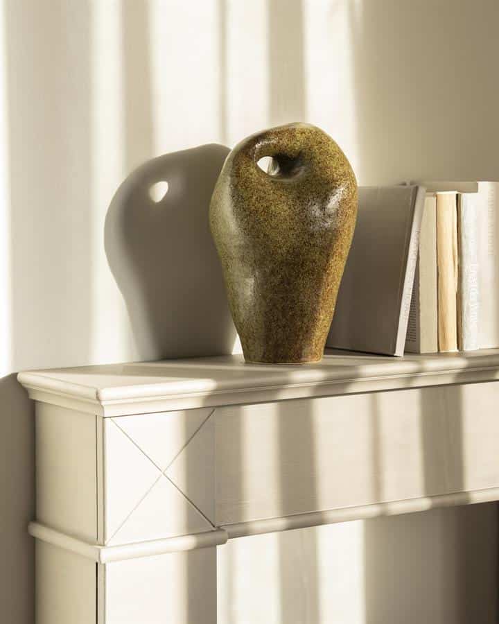 Krijtstenen vaas op witte console, modern decor, natuurlijke materialen, elegante woonaccessoire.