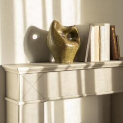 Moderne keramische vaas en romans op een wit dressoir, natuurlijk licht, stijlvolle woondecoratie.