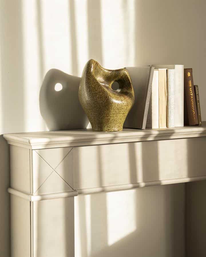 Moderne keramische vaas en romans op een wit dressoir, natuurlijk licht, stijlvolle woondecoratie.