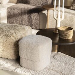 Fluwelen poef in crèmetinten als stijlvol en veelzijdig meubelstuk voor een gezellige zithoek.