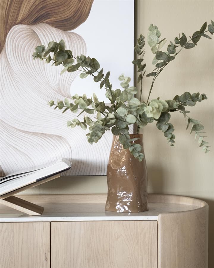 Rustieke keramische vaas met eucalyptus takken op een lichte houten meubel, elegant woningdecor, Mokana Meubelen, stijlvolle interieuraccessoires, natuurlijke sfeer, moderne en tijdloze inrichting.