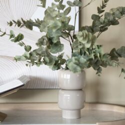 Eucalyptus in een moderne witte vaas op een houten meubel, decoratie voor een stijlvolle woonkamer.