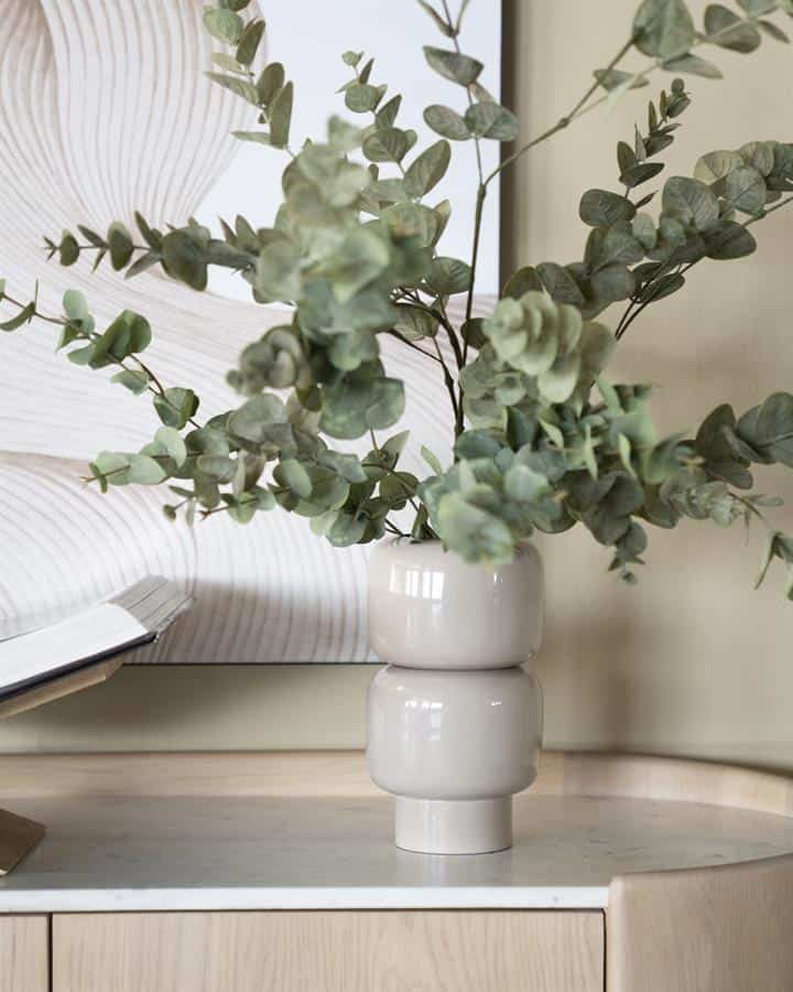 Eucalyptus in een moderne witte vaas op een houten meubel, decoratie voor een stijlvolle woonkamer.