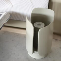 Flesvormige kaars in witte, moderne kaarshouder met strakke lijnen op marmeren oppervlakte.