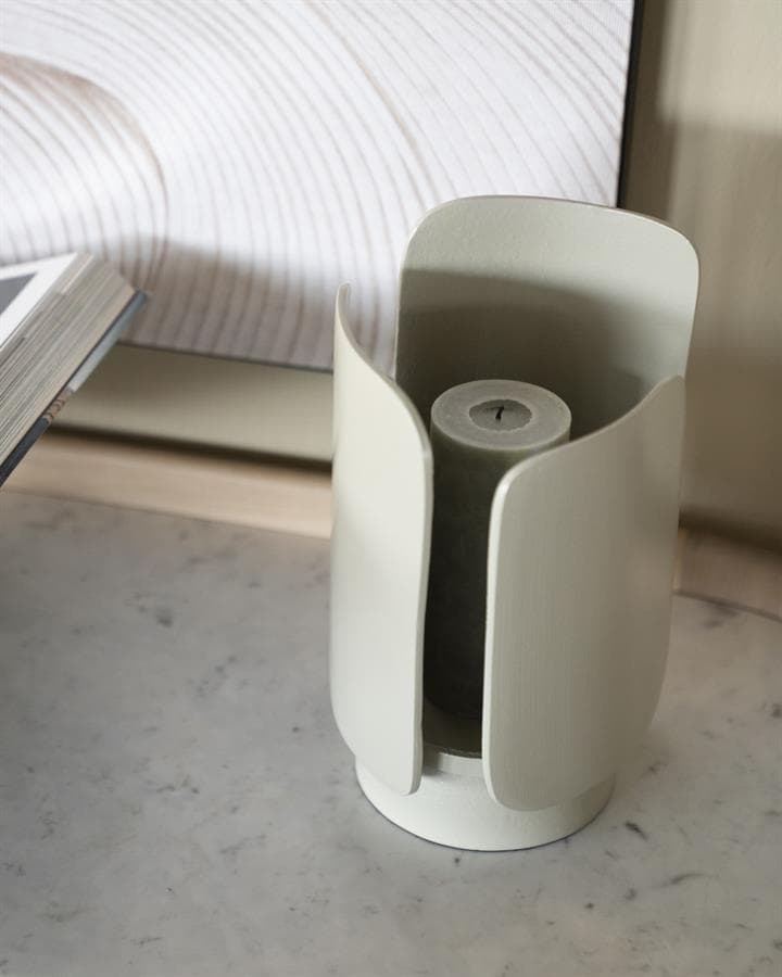 Flesvormige kaars in witte, moderne kaarshouder met strakke lijnen op marmeren oppervlakte.