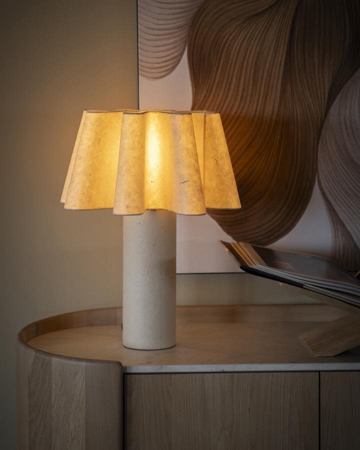 Eenvoudige houten lamp met beige lampenkap op een licht houten meubelstuk.
