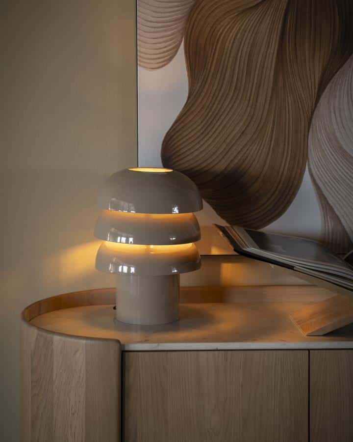 Minimalistische witte lamp op een houten sideboard met modern kunstwerk op de achtergrond, perfect voor stijlvolle woonkamers en interieurdesign.